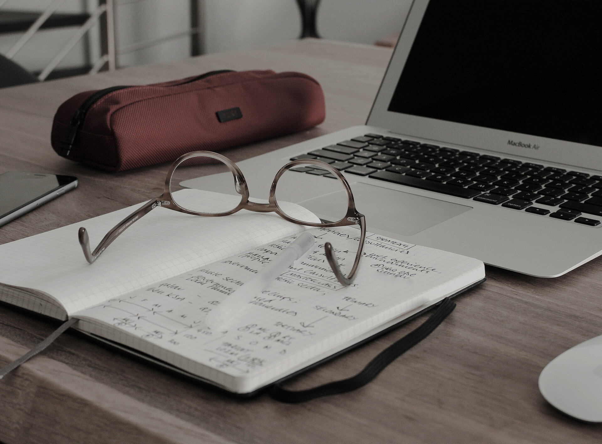 Eine Brille liegt auf einem Schreibtisch neben einem Laptop