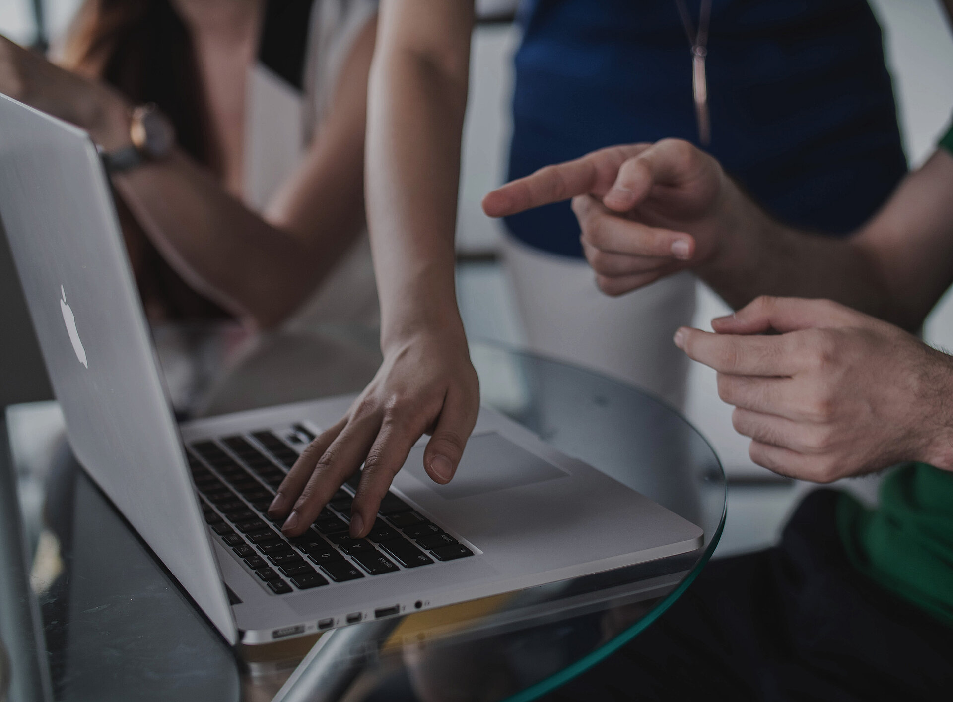 Jemand zeigt anderen Person etwas auf einem Laptop