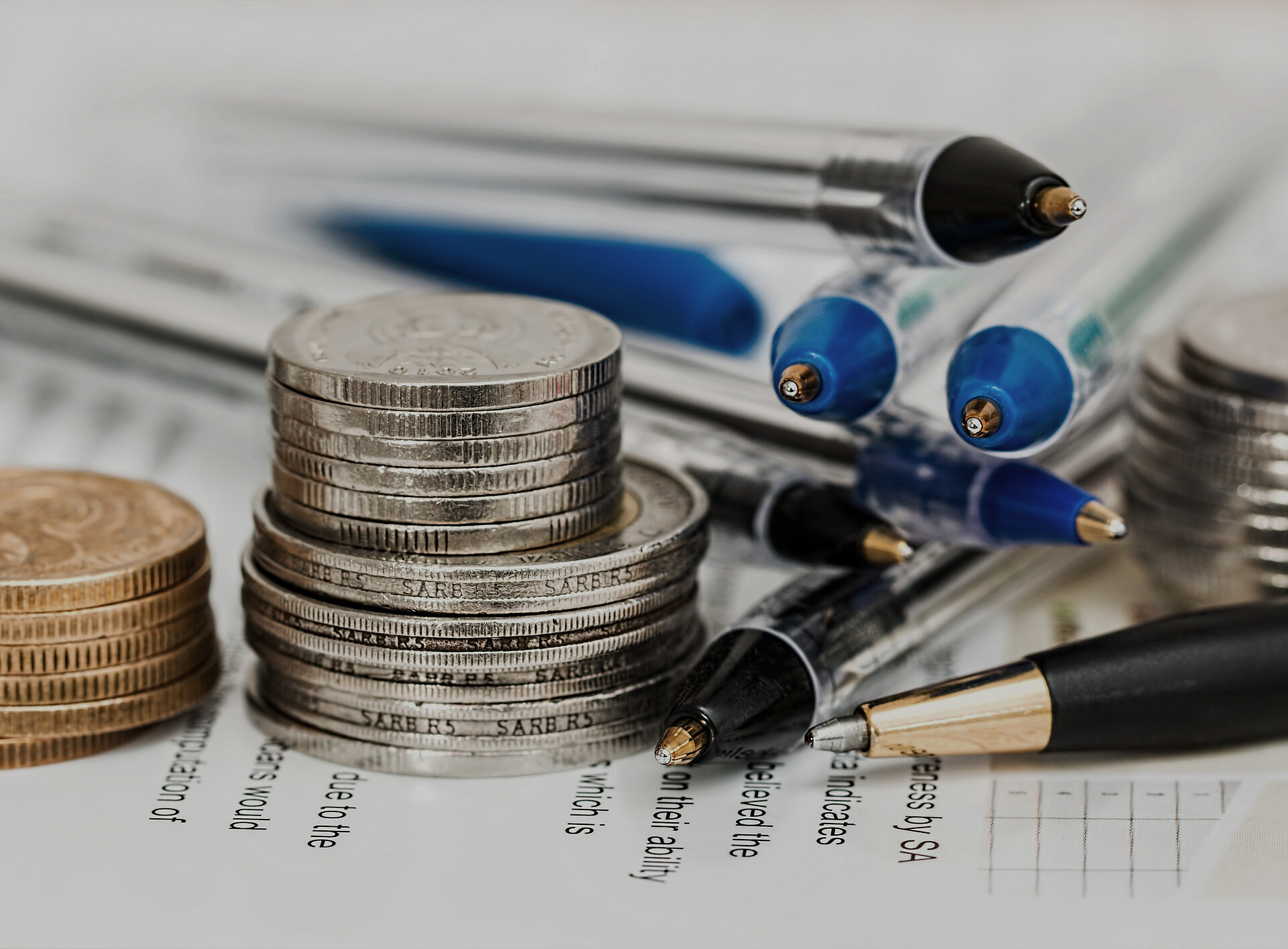 Nahaufnahme von Münzen und Stiften auf einem Schreibtisch